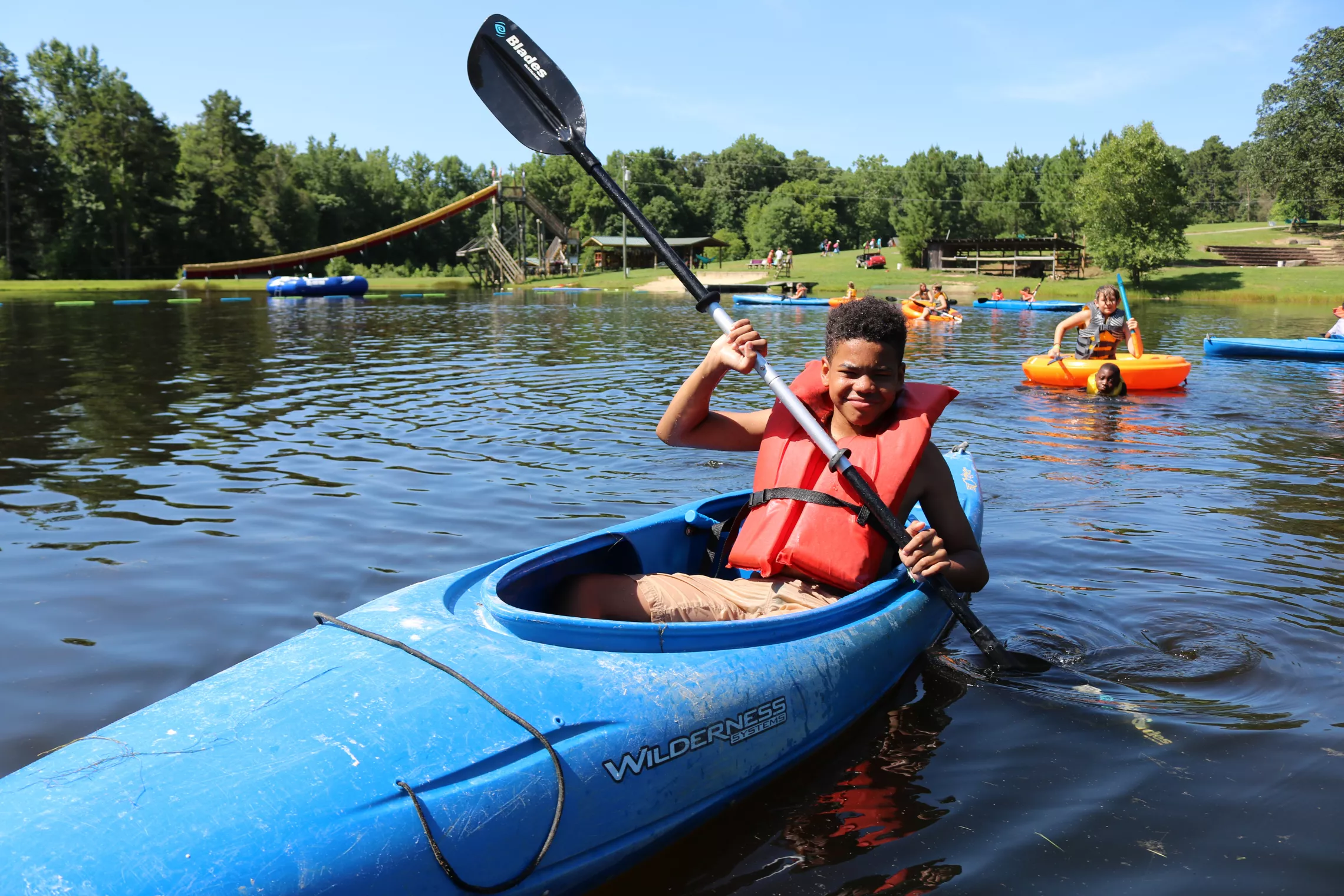 A boy kayaking on a sunny day at YMCA Camp Weaver.