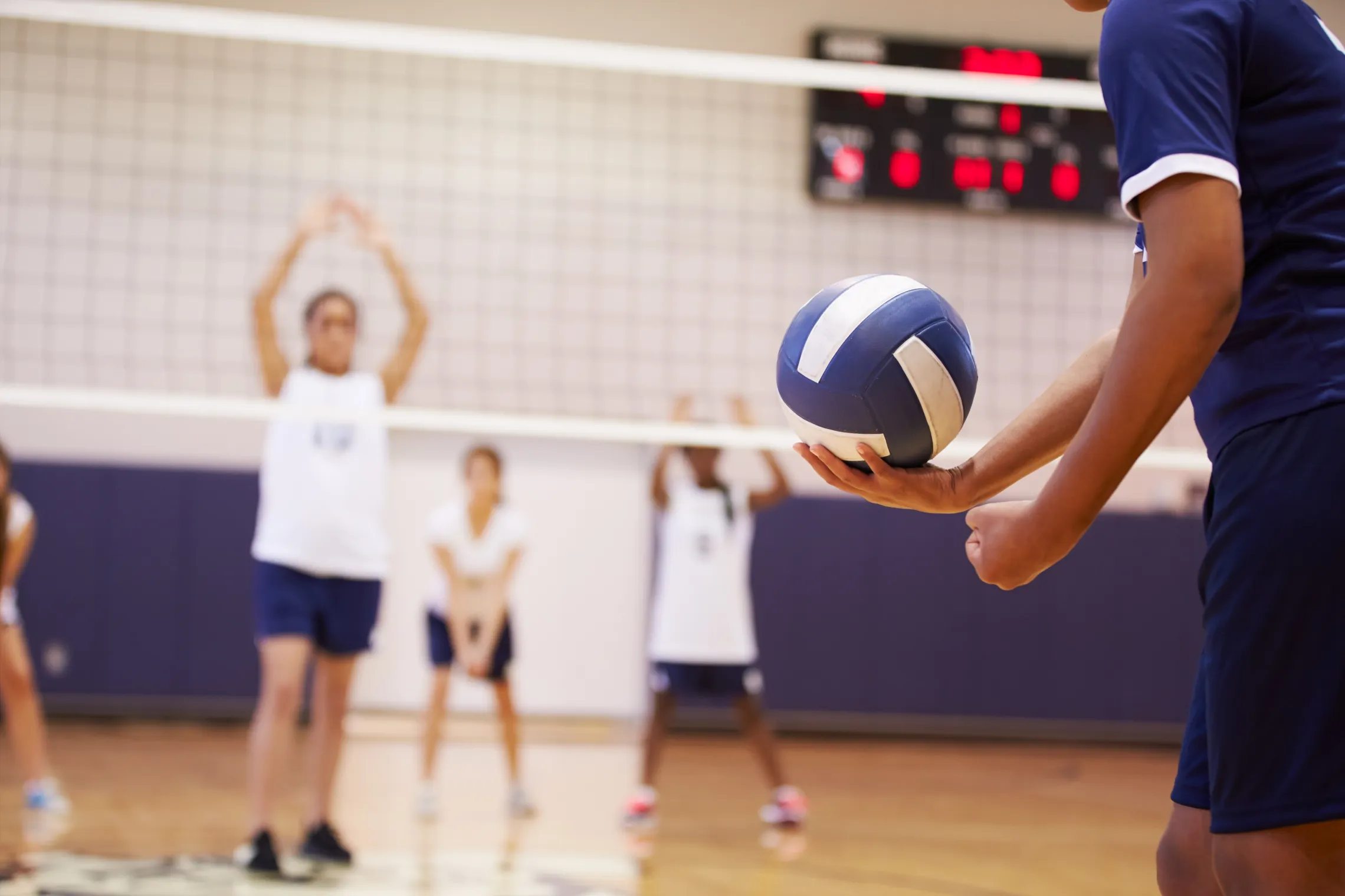 A volleyball player preparing to serve a volleyball during a match.