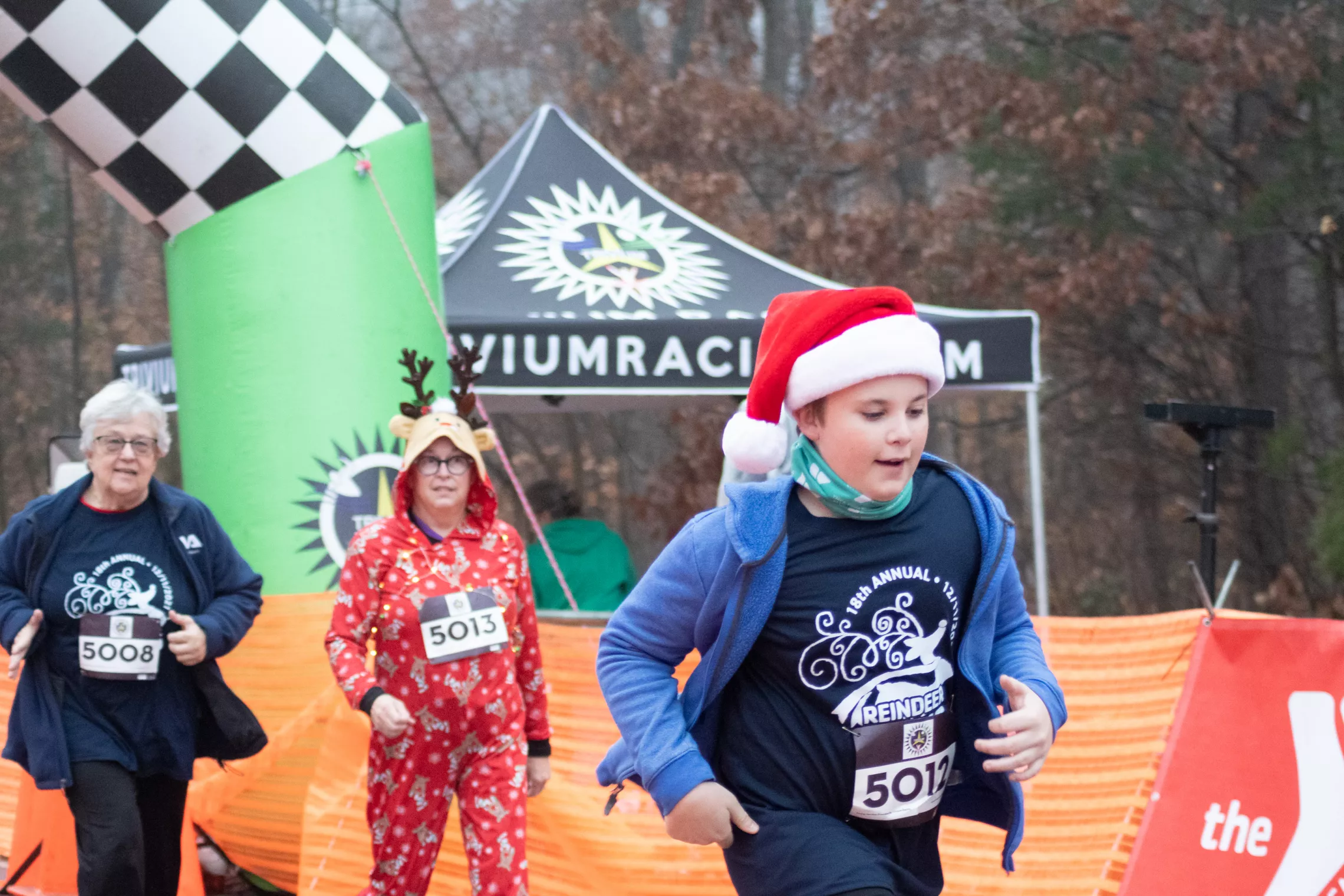 A boy wearing a Reindeer Romp shirt and a Santa hat runs during the annual Reindeer Romp race.