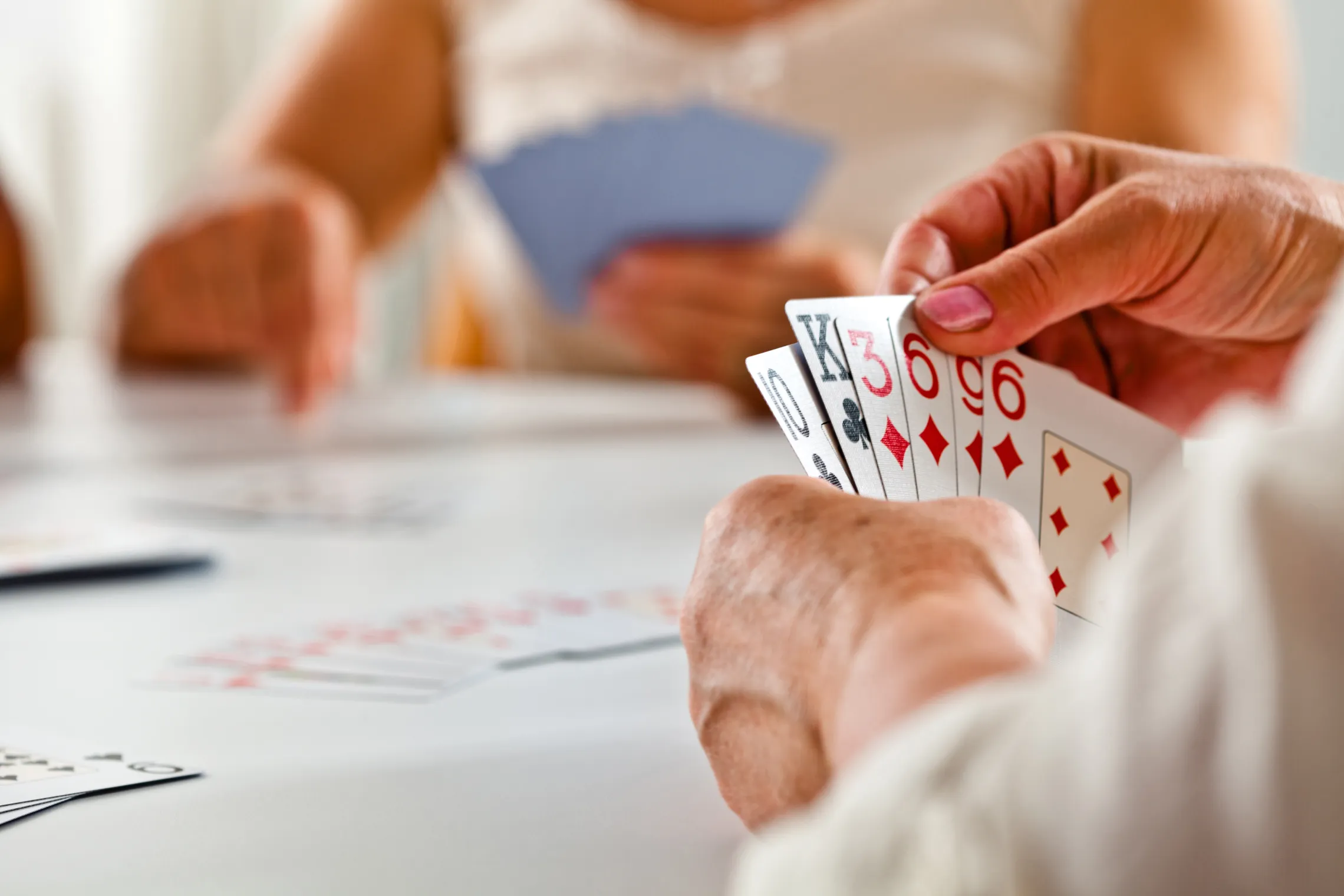 A close up photo of a senior woman's hand while she plays a card game.