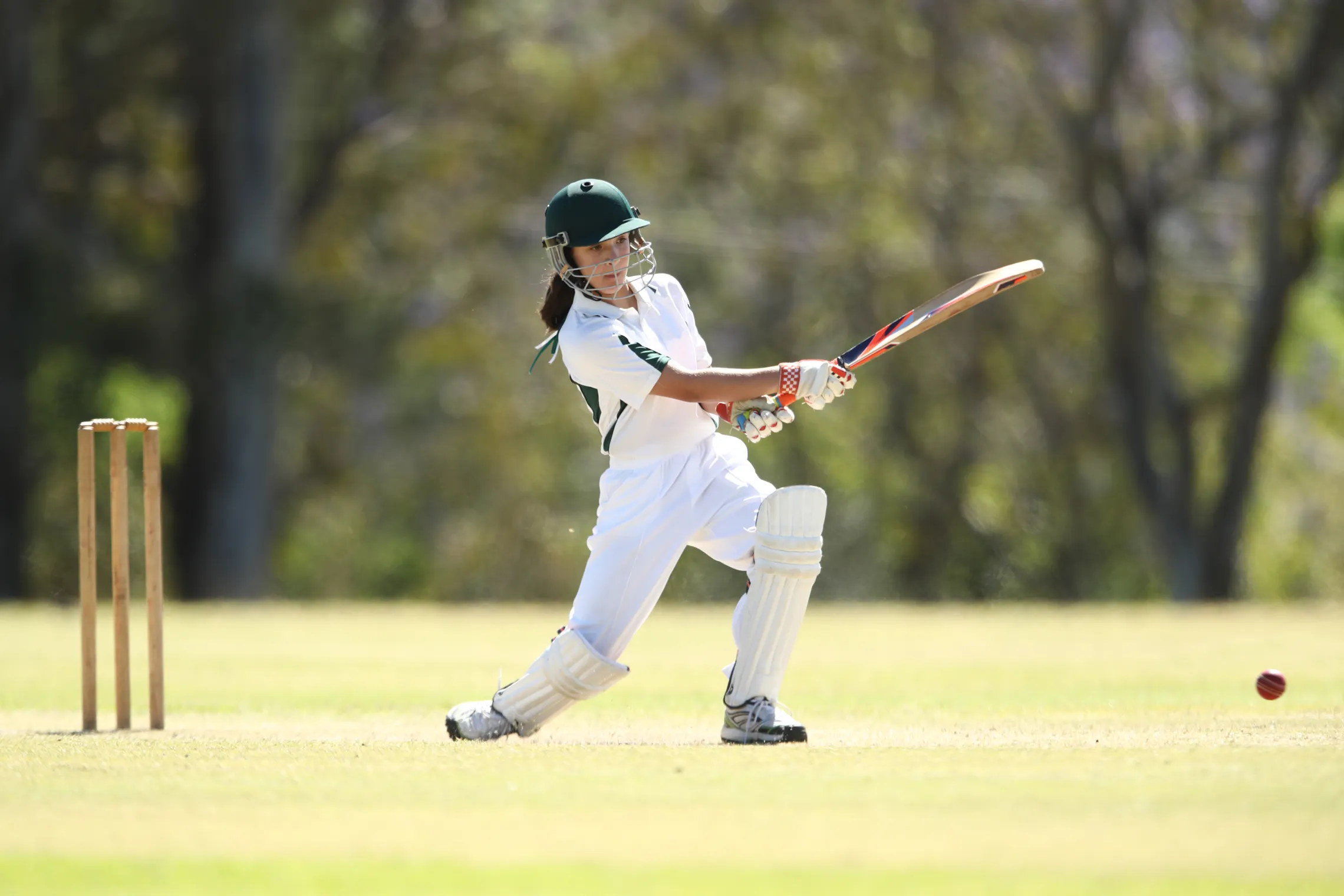 A young girl batting while playing cricket.