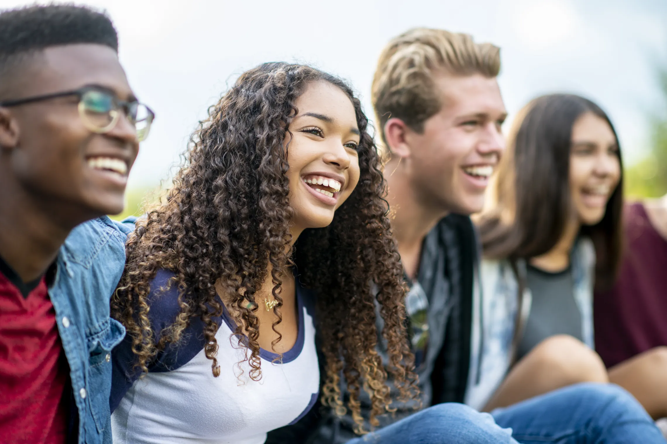 A group of teens sitting together outside.
