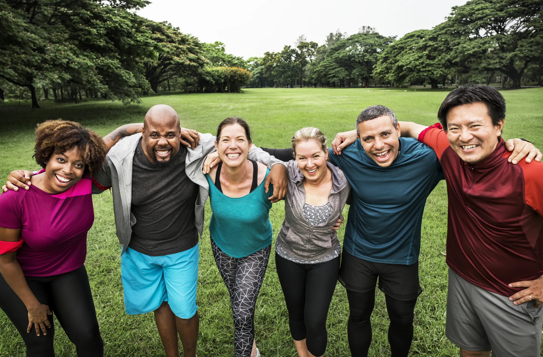 A diverse group of adults standing together outside.