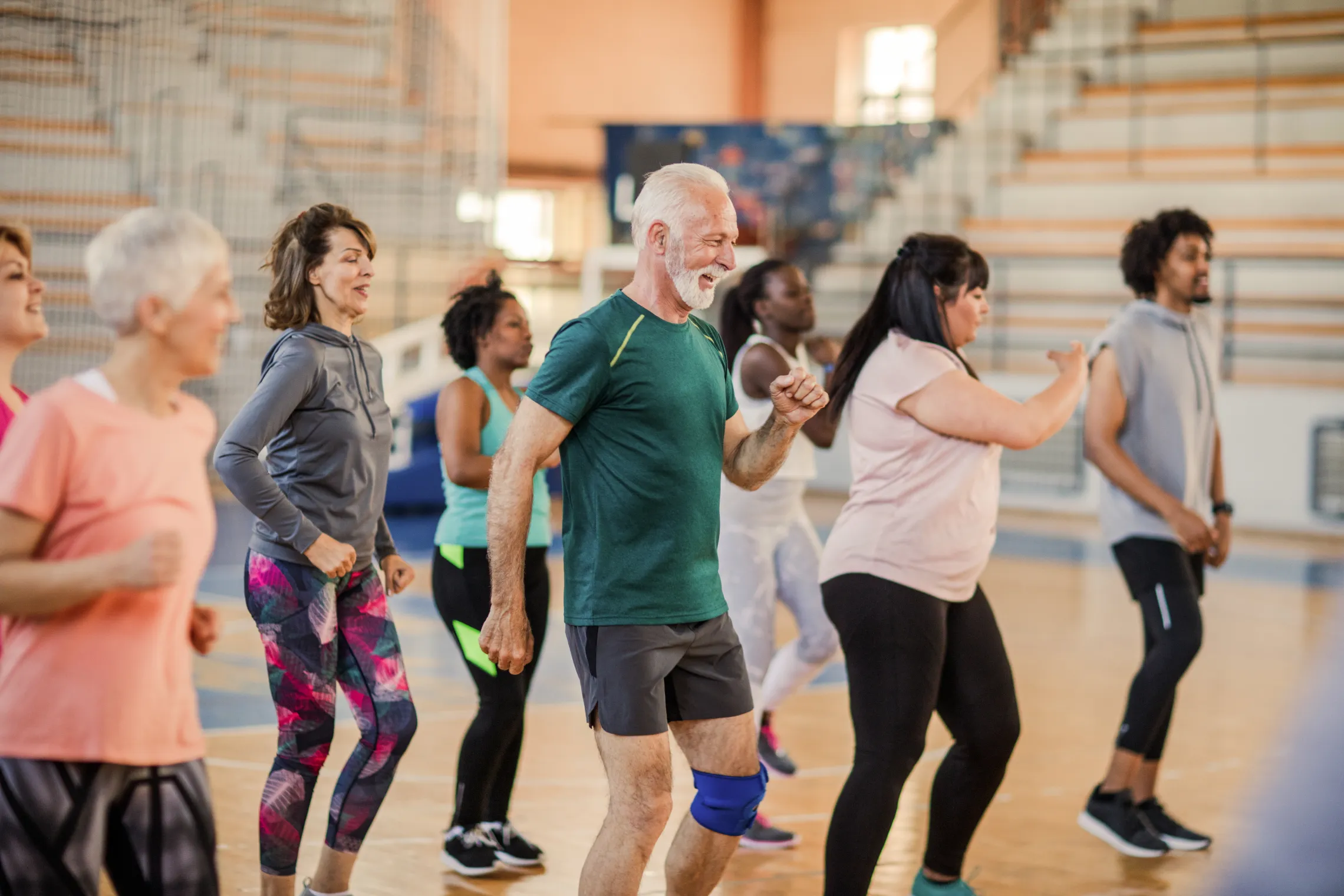 A diverse group of people dancing together in a gym.