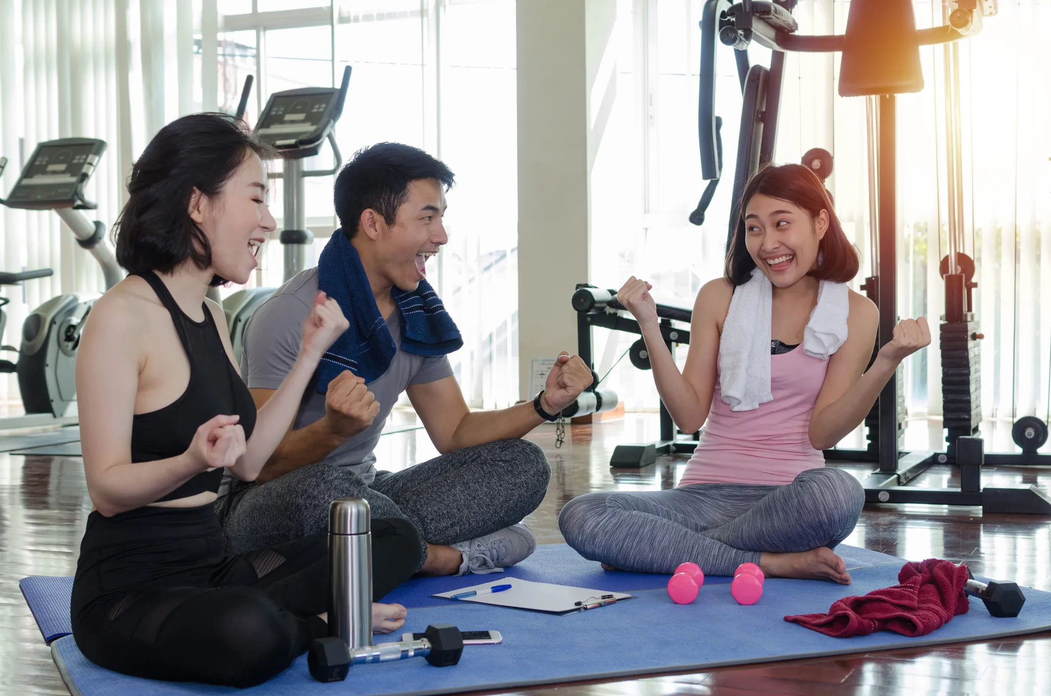 group of young adults in gym fitness room together having fun and smiling