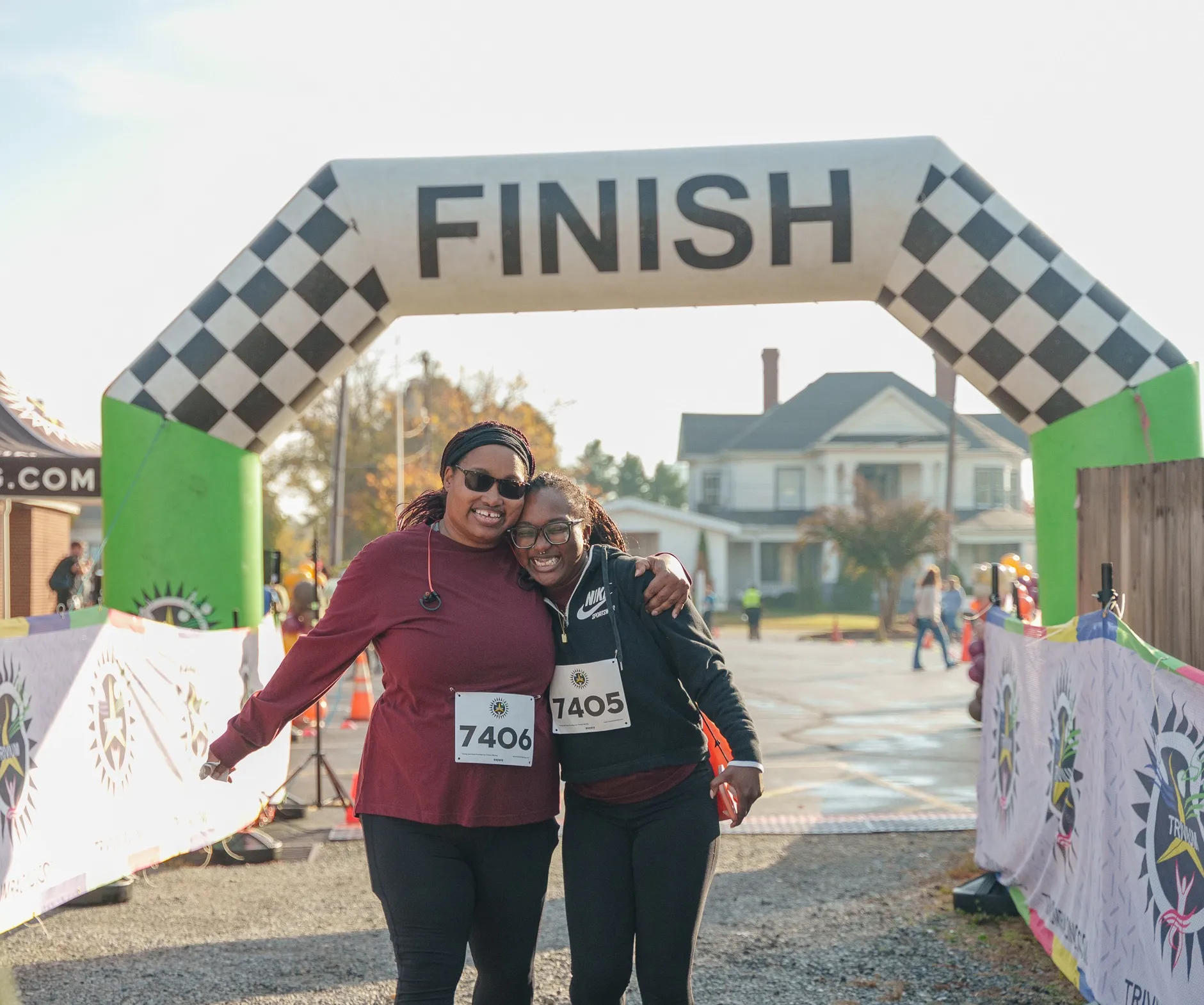 Two women standing together at the finish line during the Reidsville Family YMCA's Turkey Trot road race. They are smiling at the camera.