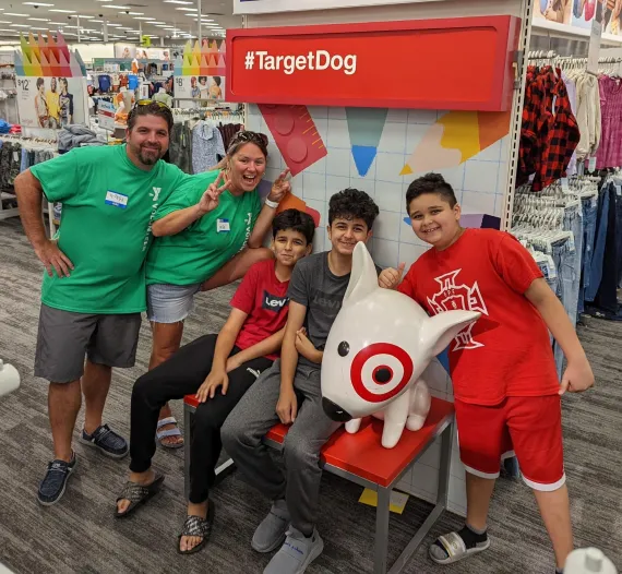 Two Bright Beginnings volunteers smile for a photo in Target with three children shopping for school supplies.