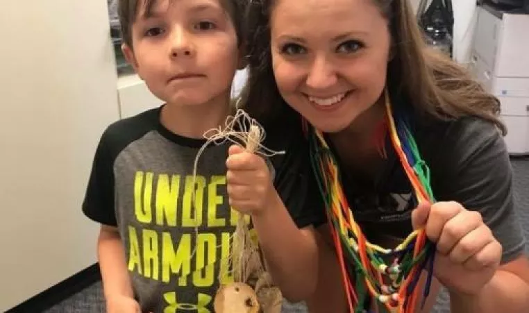 camp counselor with camper doing crafts