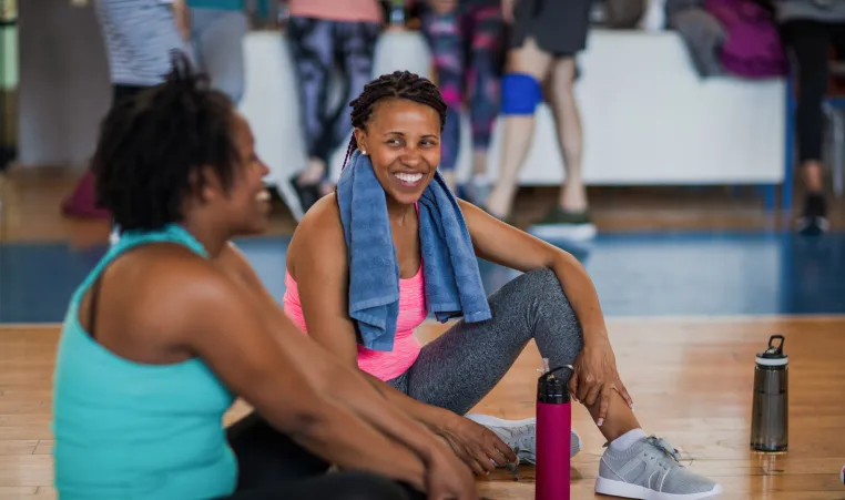 Two women smile at each other as they attend an exercise class.