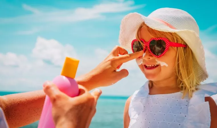 adult putting sunscreen on childs face