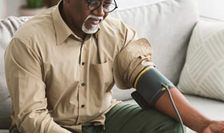 Senior African Male Measuring Arterial Blood Pressure Having Hypertension Indoor