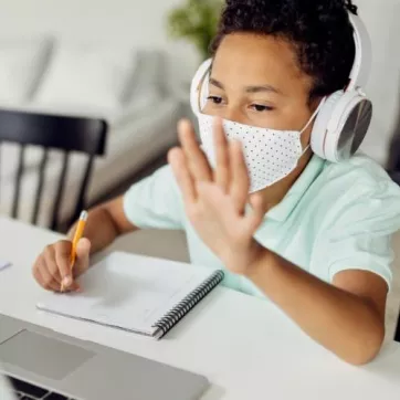 child waving during remote learning on screen