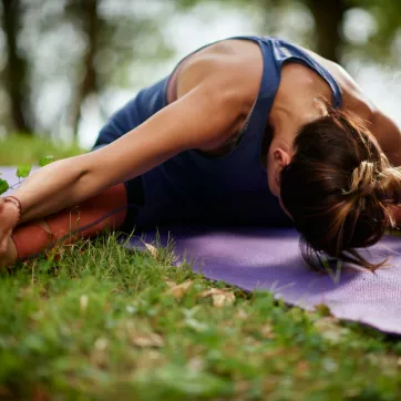 A woman does a yoga stretch outside.