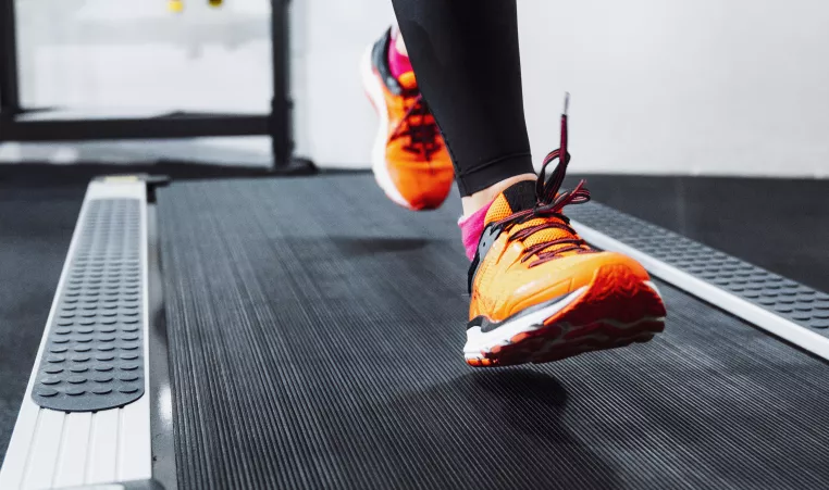 A woman wearing orange shoes running on a treadmill.