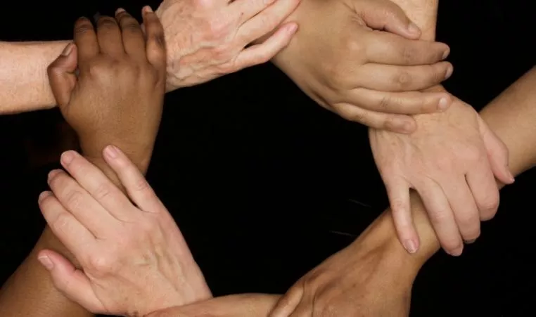 A series of hands clasped together in a circle.