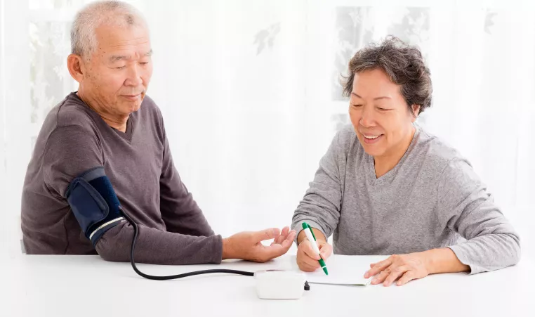 A senior couple monitoring their blood pressure at home.