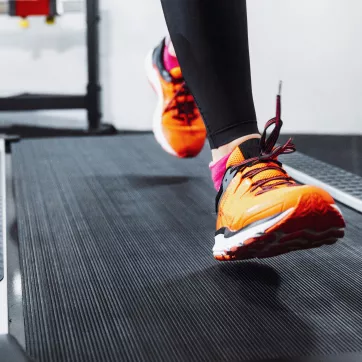 A woman wearing orange shoes running on a treadmill.