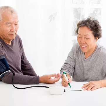 A senior couple monitoring their blood pressure at home.