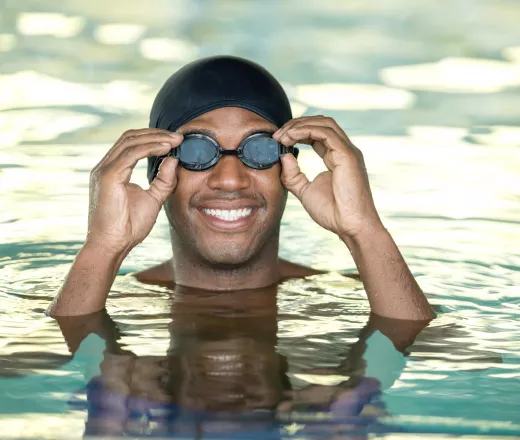 A man wearing swimming goggles while in a pool.