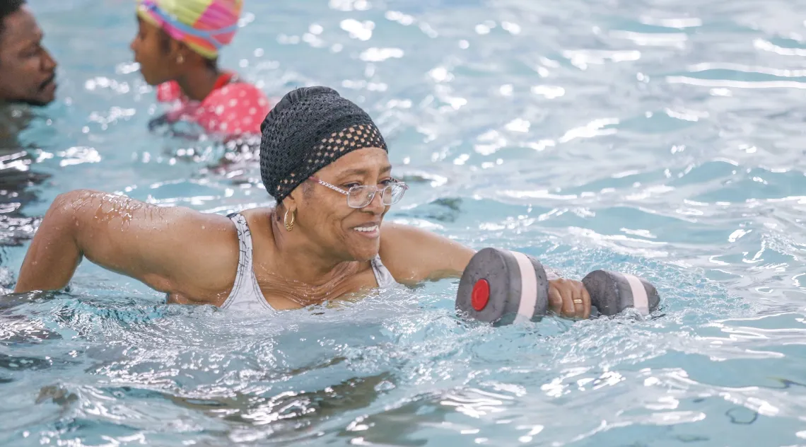 A woman in a water exercise class at the Bryan YMCA smiles while working out.