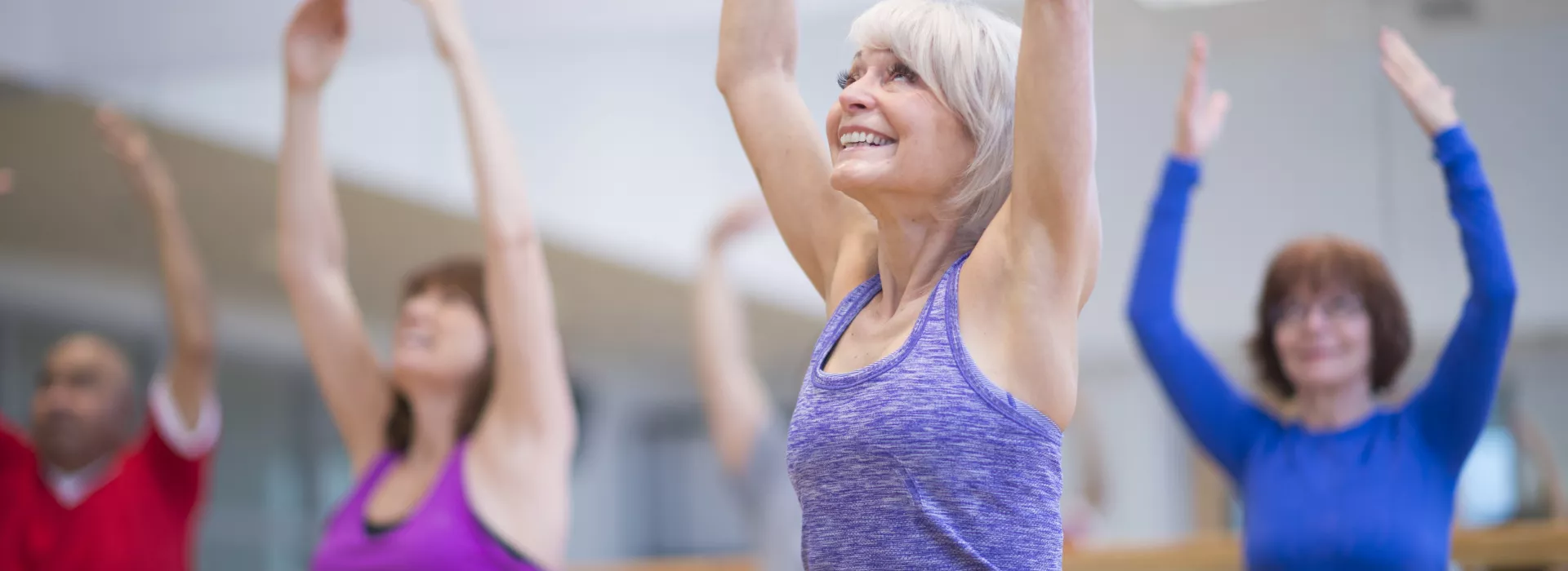 A group of senior women participate in a yoga class.