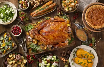 A holiday meal with a spread of foods like turkey, cranberries, and pies.
