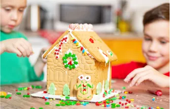 Two young boys build a gingerbread house together