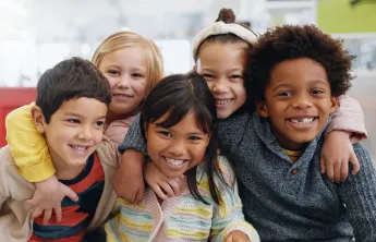 A diverse group of young children sitting together and smiling at the camera.