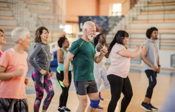 A diverse group of people dancing together in a gym.