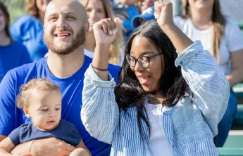 A mother and father at a sporting event with their young child.