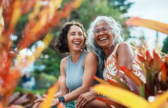 Two women sitting outdoors laughing together.