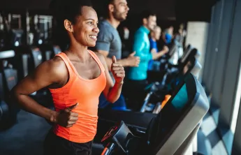 A woman running on a treadmill at the gym.