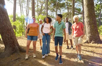 A diverse group of people ranging from teenager to seniors walking together in the forest.