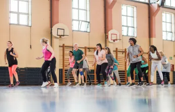 A diverse group of people dancing together in a gym.