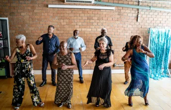 A group of senior friends laughing and dancing together.
