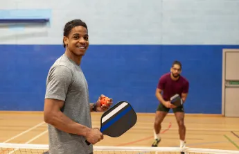 Two men in gym playing pickleball