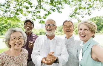 A group of seniors standing outdoors laughing together.