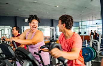 Two people on the elliptical machine in wellness center