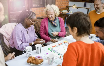 A group of adults playing a board game together. They are laughing.