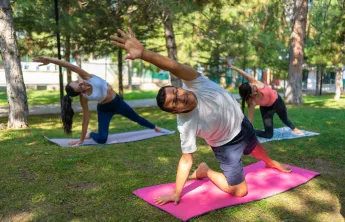 A man in a group exercise class doing yoga outdoors.
