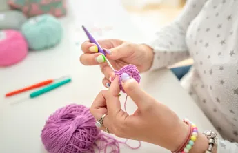 A close-up view of a woman's hands as she is crocheting.