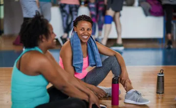 Two women smile at each other as they attend an exercise class.