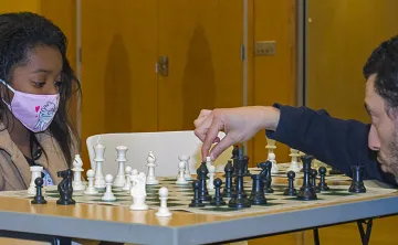 Grandmaster Gabriel Flom plays chess with kids at Hayes-Taylor YMCA.