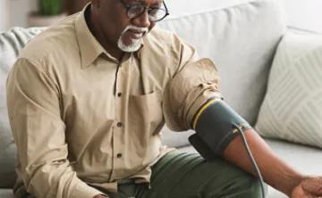 Senior African Male Measuring Arterial Blood Pressure Having Hypertension Indoor