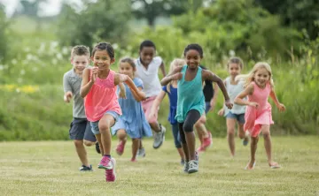 A group of children smiling while they play outside.