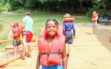 Kid with an orange lifejacket at summer camp.
