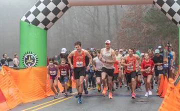The Reindeer Romp starting line. A crowd of people wearing running gear are running toward the camera as the race starts.