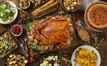 A holiday meal with a spread of foods like turkey, cranberries, and pies.