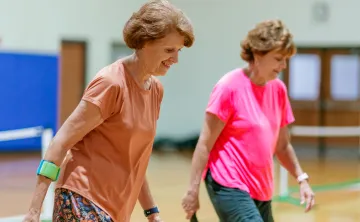 Two women playing pickleball together on a team.