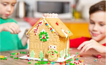 Two young boys build a gingerbread house together